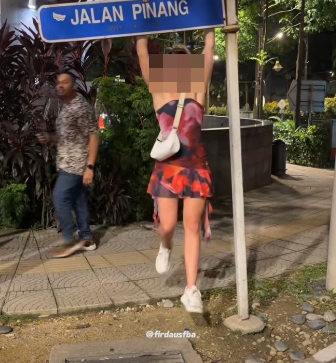 Pelancong Wanita Bergayut Pada Papan Tanda Sehingga Bengkok, Warga Tempatan Berang